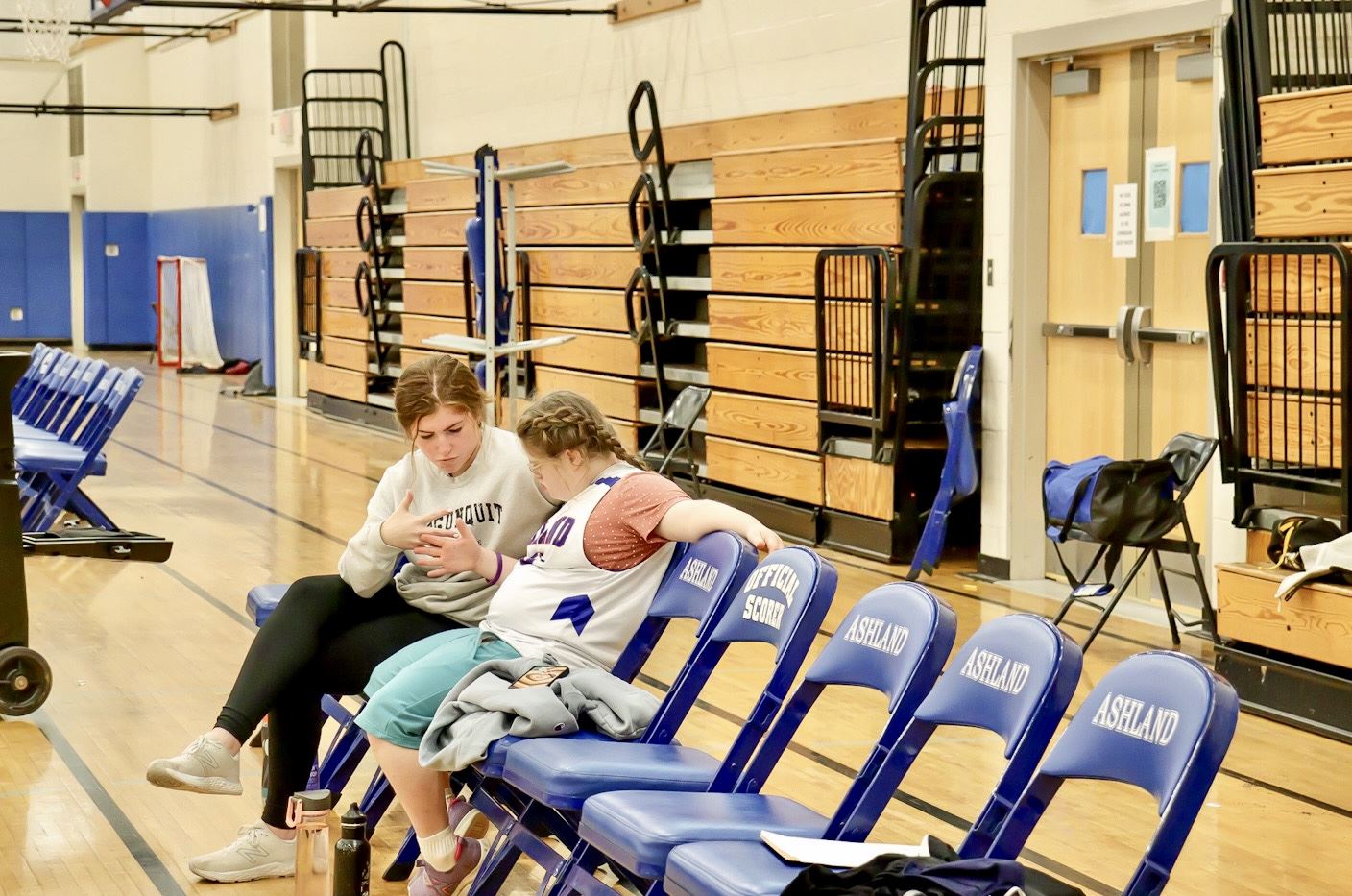 A Unified basketball partner and student-athlete shake hands as they sit on the bench A Unified basketball partner and student-athlete shake hands as they sit on the bench