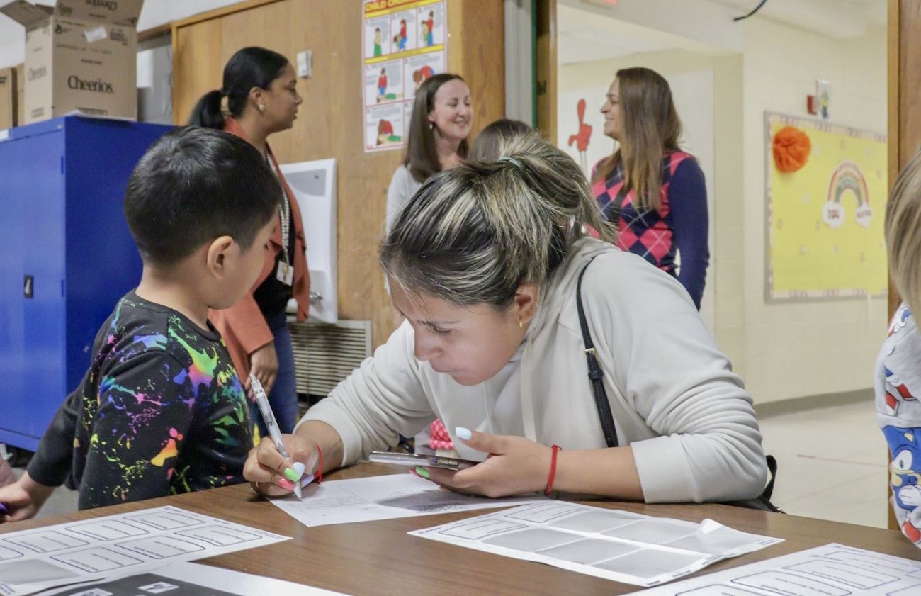 A mother references her phone as she signs in for a Famiy Night at Warren with her child